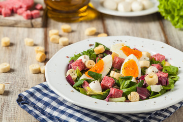 Delicious Italian salad with salami, egg, crostini and mozzarella.