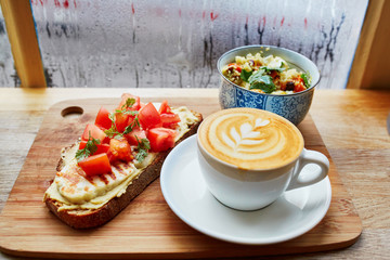 Hummus and tomato sandwich, salad and fresh hot cappuccino coffee
