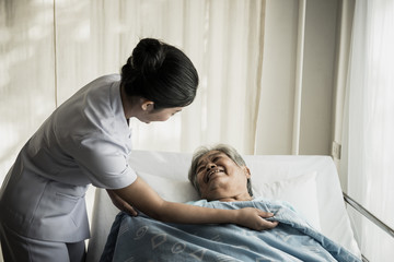 Young nurse take care of senior patient In Hospital Room