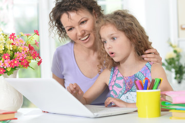 mother and daughter using laptop