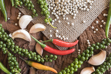 Thai spices such as fresh peppercorn, dried pepper, chilli and garlic placed on old wooden background