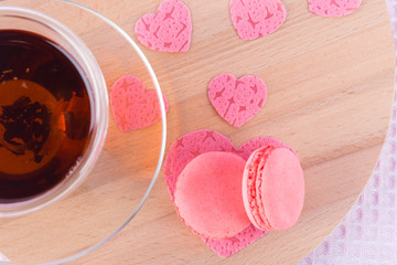 mug of tea on a wooden board with two cookies and pink hearts