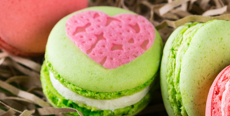 pink heart lies on a green macaron, background for a day of lovers