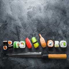 Food concept of sushi, rolls and knife on grey background. Flat lay, Top view