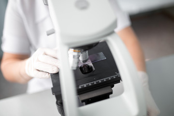 close up of scientist hands with microscope, examining samples in laborator