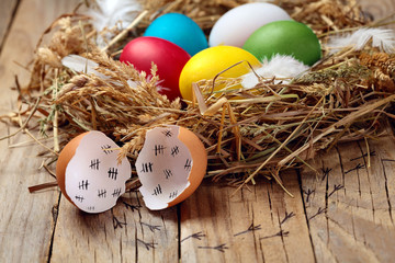 Concept of an escaped from egg of young chicken.Colourful Easter eggs in the nest. On wooden rustic...