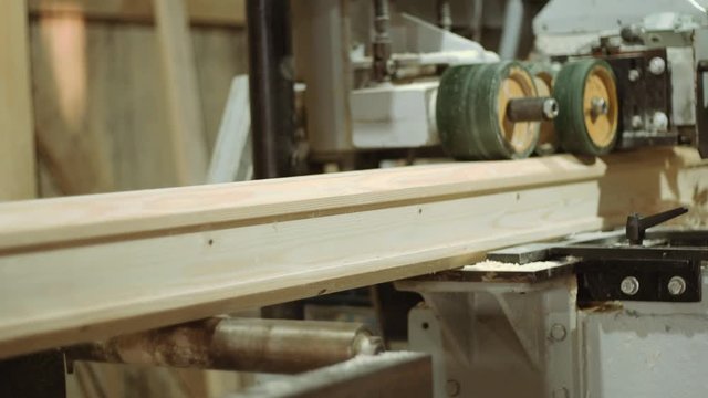 Spinning spiked wheels of bar refiner machine working on wood at woodwork production, close up