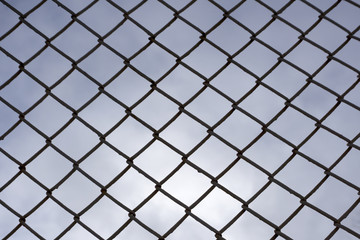 several rows of metal mesh with square cells used as a guard, in the background in the background of the sky the lines from another grid are out of focus