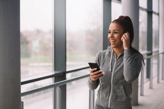 Young Fitness Woman Using Phone After Workout Indoors.