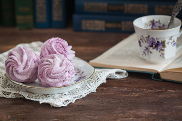 Homemade marshmallow or zephyr with a cup of tea over the wooden background.