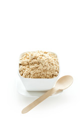 Whey protein powder in bowl on plate against white background