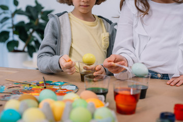 cropped shot of kids painting easter eggs together