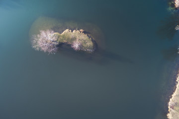 great drone view of a beautiful small island in the middle of a small frozen deep blue lake