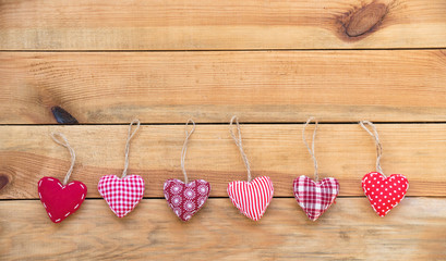 Line of red fabric hearts hanging on old wood background