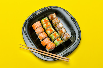 Black plate with various rolls on a yellow background. Top view