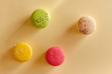 Four multicolored macarons on a yellow background