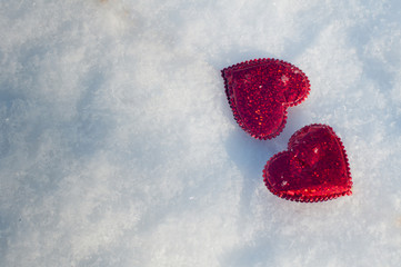 St Valentine's day card. Two red hearts laying on white snow. Top view, space for text