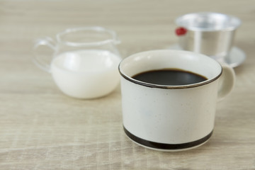 CERAMIC COFFEE CUP WITH DRIP FILTER
Small ceramic coffee cup with milk jar and drip filter on a wood table.