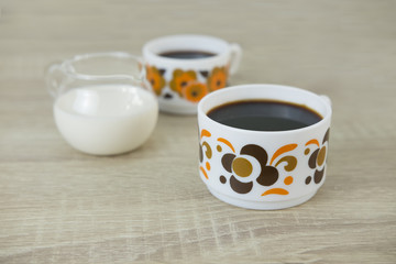 Obraz na płótnie Canvas TWO RETRO COFFEE CUP Two small retro coffee cups filled with black coffee, milk jar on a wood table. 