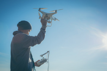 Man operating a drone with remote control. Dark silhouette against colorful sunset. Soft focus.