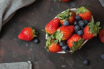 Full of ceramic bowl with blueberries and strawberries  on the stone table.