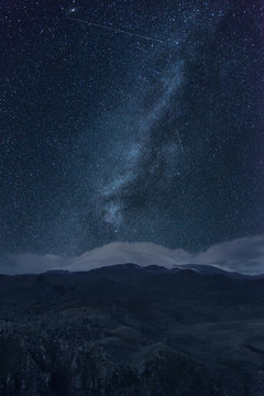 Night sky with milky way over mountains.