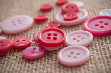 boutons de couture de couleur rose sur toile de jutte