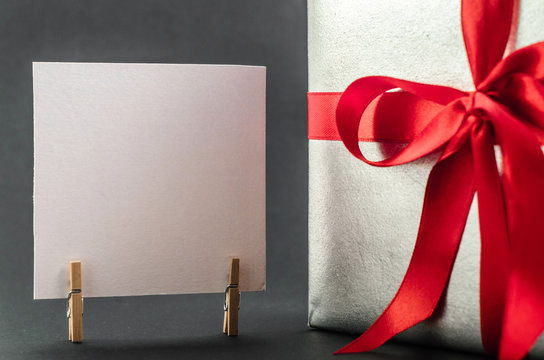 Gift in silver packaging with red ribbon and greetings with Valentine's day. Copyspace