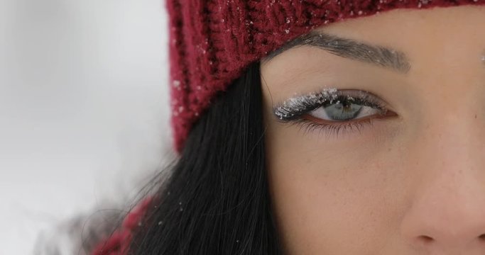 Close-up of woman open her eyes with snow on big eyelashes