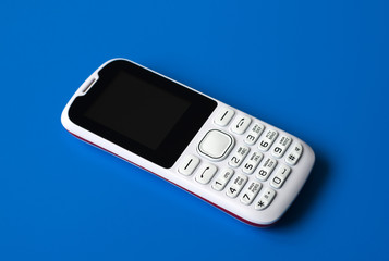 White cell phone with buttons on blue background.
