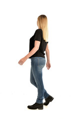 full length portrait of blonde girl wearing simple black shirt and jeans, standing pose wit back to...