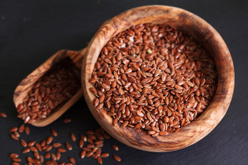 Organic flax seed in wooden bowl on black slate background copy space. Linum usitatissimum
