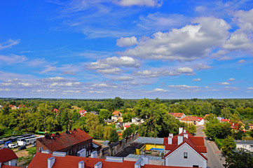 Błękitne niebo, białe chmury, zielone drzewa i czerwone dachy domów. © W Korczewski