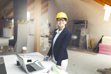 very pretty young female architect wearing yellow helmet is planning a loft in a house