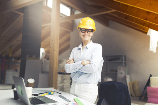 very pretty young female architect wearing yellow helmet is planning a loft in a house