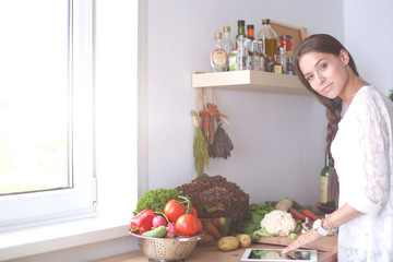 Young woman using a tablet computer to cook in her kitchen . Young woman