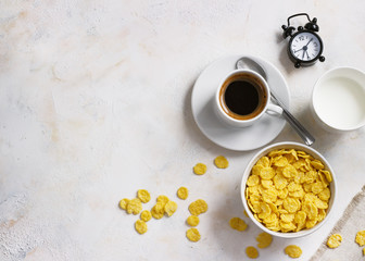 Corn flakes, coffee, alarm clock on a light background, breakfast
