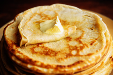 Russian Maslenitsa, Shrovetide, pancake week, carnival, shrove, pancake day. a stack of pancakes with butter upstairs on plate, on wooden background, close-up