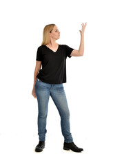 full length portrait of blonde girl wearing black shirt and jeans, standing pose isolated on a white background.