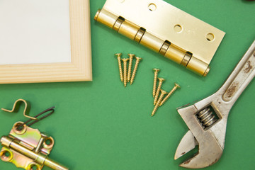 Home, House Repair, Redecorating, Renovating Concept. Door hinges, metal screws and a wrench, green background with copy space, top view, flat lay