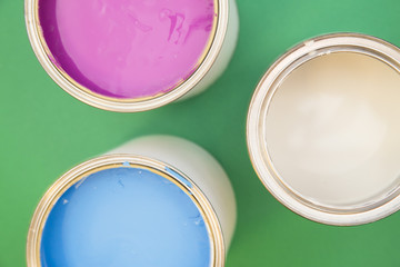 Painting, Redecorating House Concept. Tin cans of white, blue and pink oil paint, green background with copy space, top view, flat lay