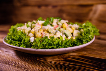Ceramic plate with salad from crab sticks on wooden table