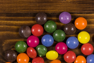 Colorful button shaped candies filled with chocolate on wooden table
