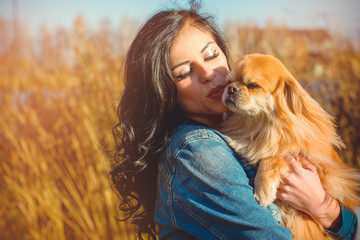 Young woman with her dog walking in the forest at sunny spring day