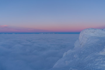 Beautiful sunset above clouds in snow covered Low Tatras mountains during susnet in winter