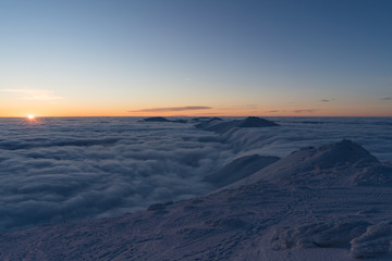 Beautiful sunset above clouds in snow covered Low Tatras mountains during susnet in winter
