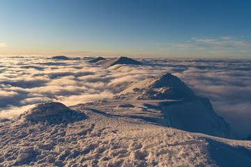 Beautiful sunset above clouds in snow covered Low Tatras mountains during susnet in winter