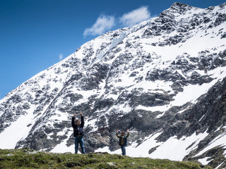 children on top of a mountain raise their hands to the sky, on the mountain background with snow