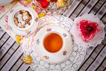 Porcelain cup of tea with lemon and sweets