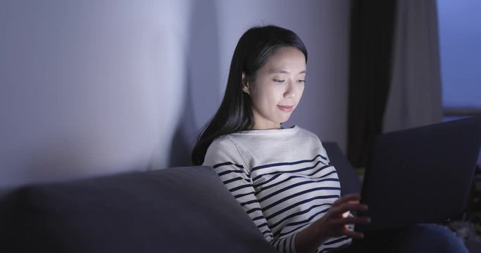 Woman using laptop computer at home in the evening